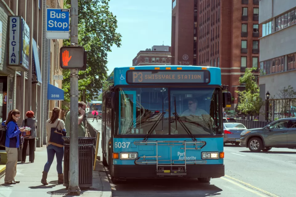 Bus stop in Pittsburgh, Pennsylvania with blue bus and passengers boarding